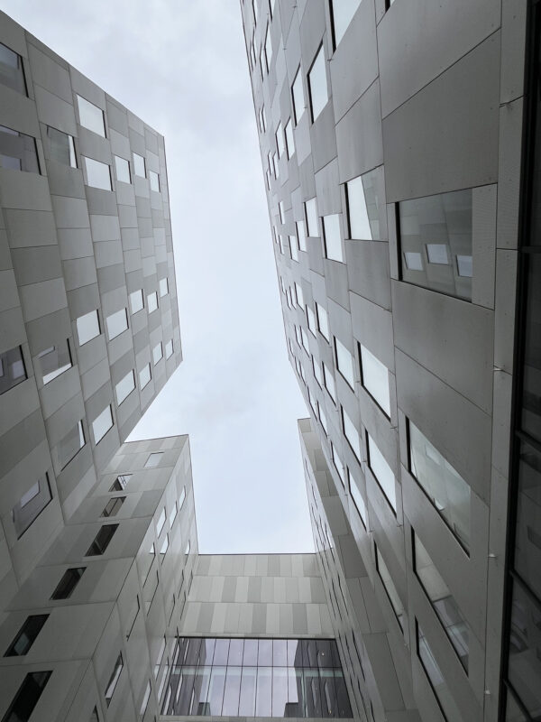 A shot from below ground looking up to a grey sky in between two tall buildings.