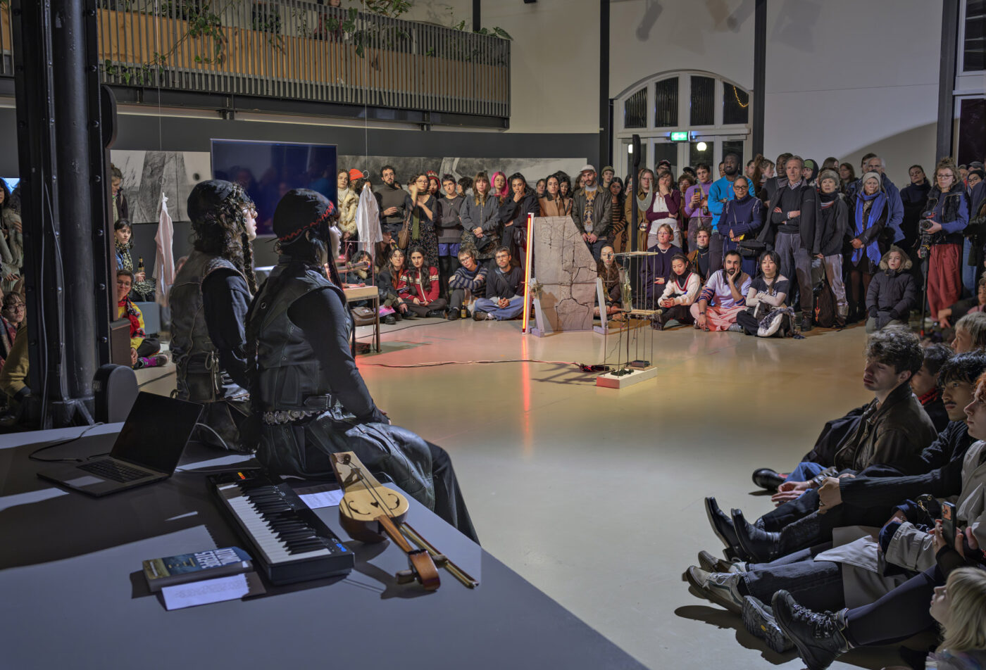 Performance van kunstenaars-duo buulbuul in de tentoonstelling Between Fires: Irradiated Imaginations and Anti-Nuclear Solidarities (2026) samengesteld door Fabienne Rachmadiev bij Framer Framed, Amsterdam. Foto: © Marlise Steeman / Framer Framed